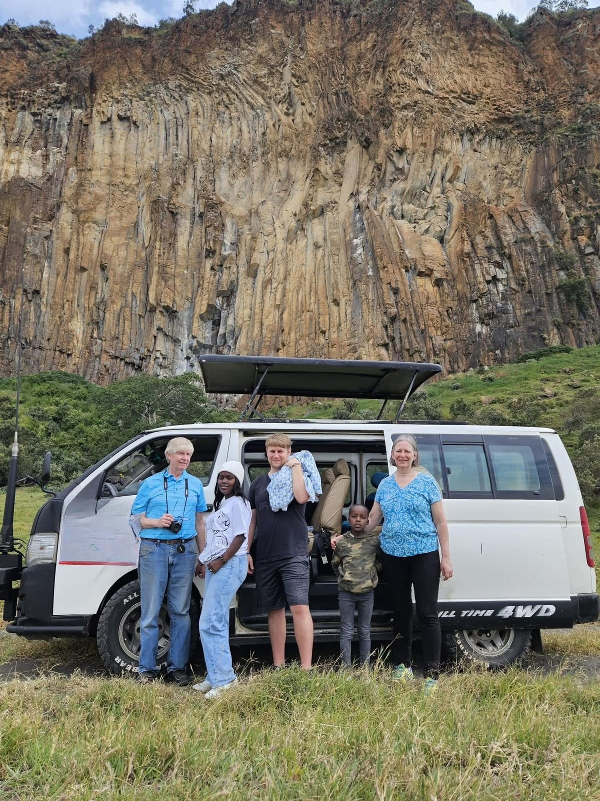 A family beside their safari vehicle on a Kenyan cliffside road