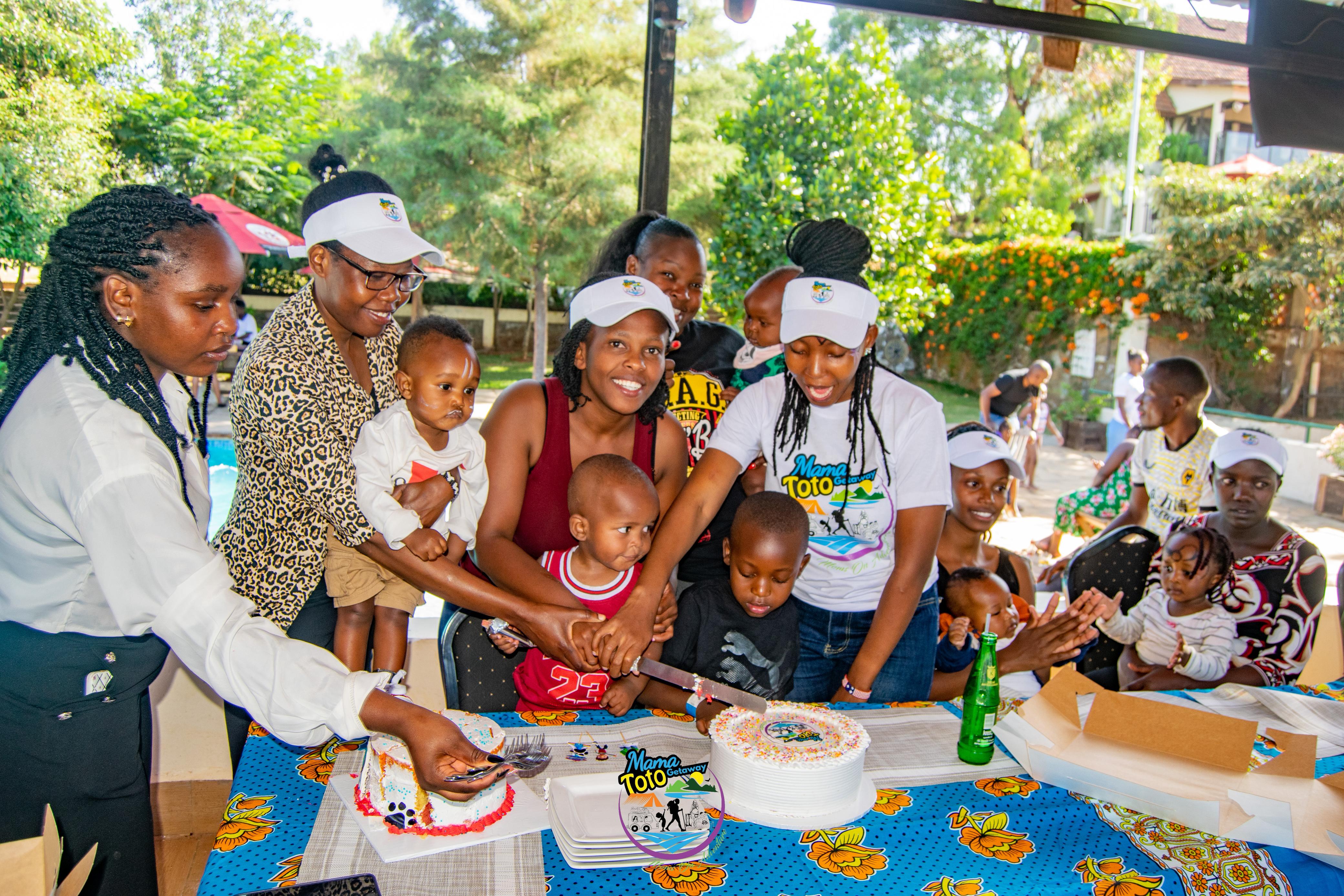 Moms and children cutting Mama Toto cake